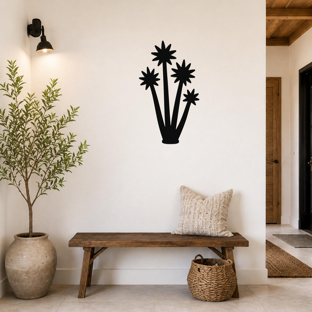 Black metal yucca wall art with star-shaped leaf cutouts, mounted on a white wall above a wooden bench in a living room.
