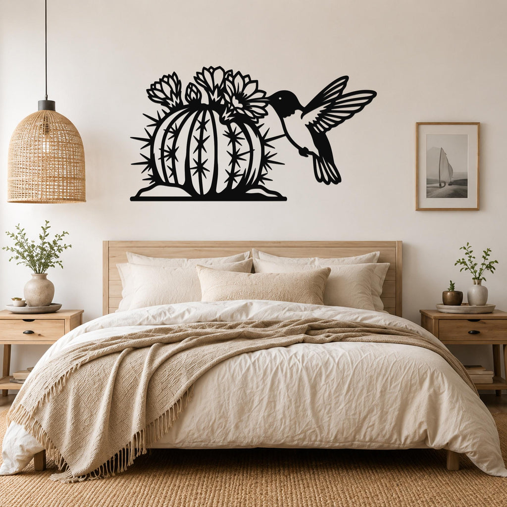 Black metal wall art featuring a hummingbird and flowering barrel cactus cutout, mounted above a bed in a neutral bedroom.