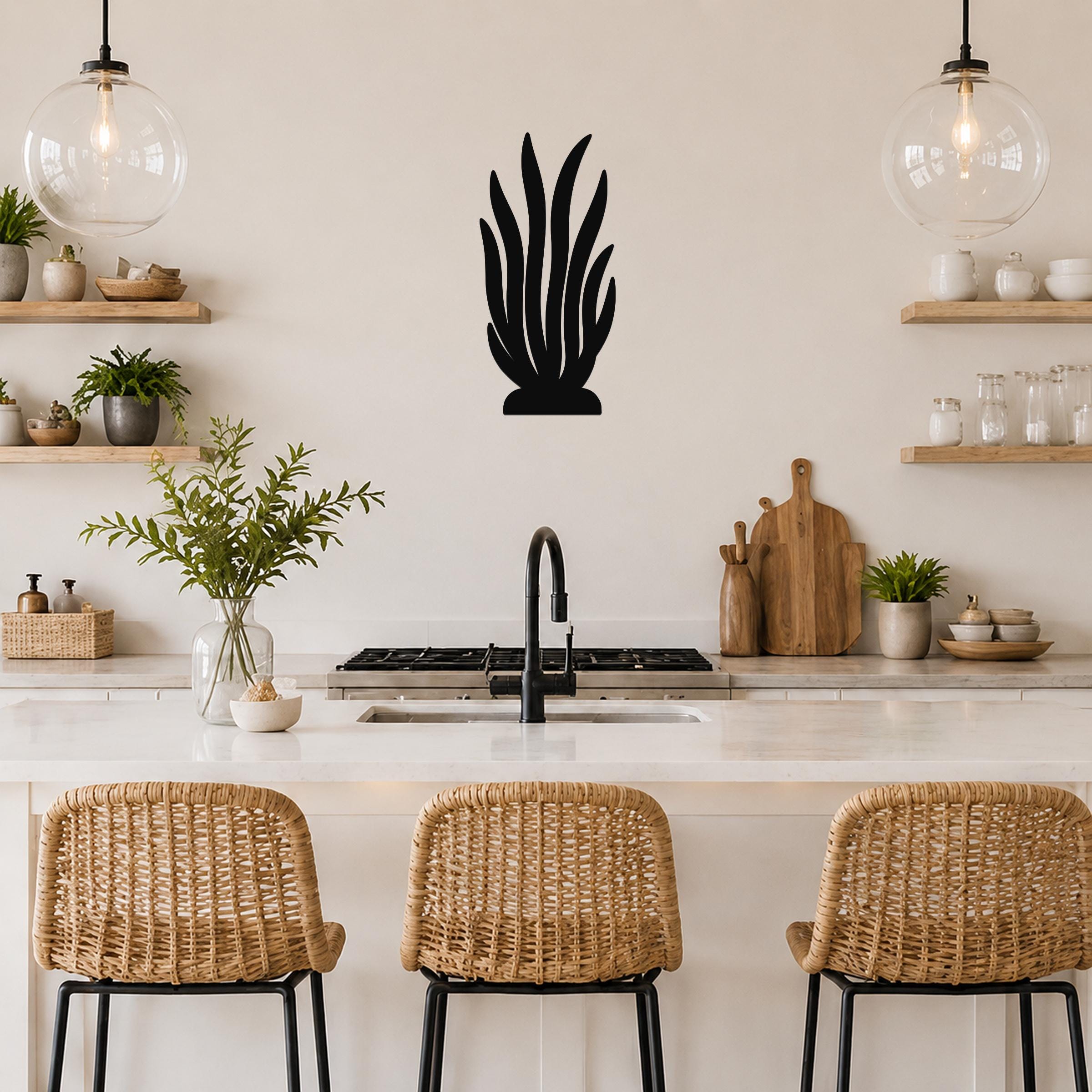 Black metal kelp wall art with layered leaf cutouts, mounted on a kitchen wall above a counter.