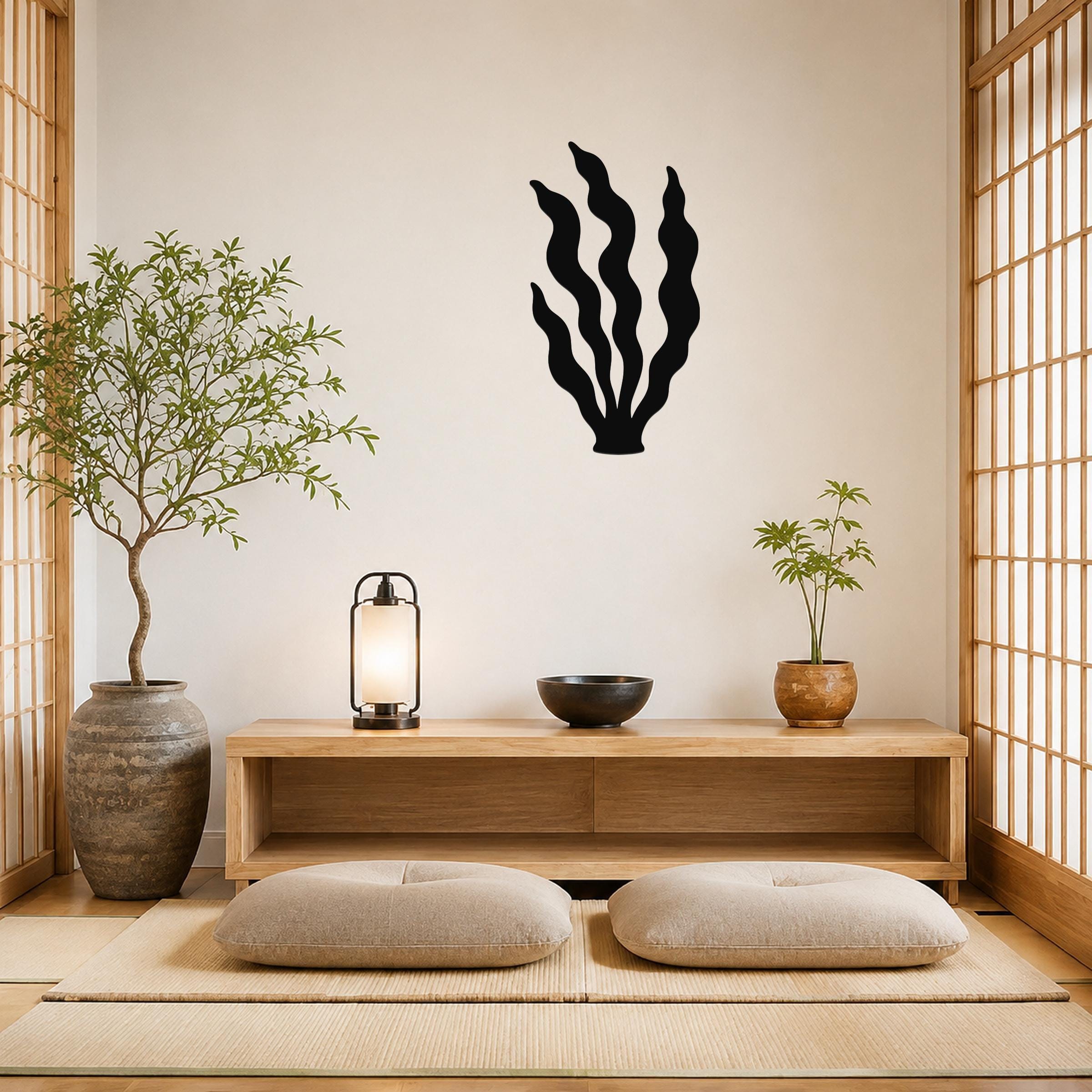 Black metal kelp wall art with wavy blade cutouts, mounted on a beige wall above a wooden console in a minimalist living room.