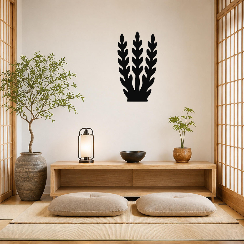Black metal wall art with a kelp or seaweed silhouette design, mounted on a beige wall above a wooden console in a minimalist room.