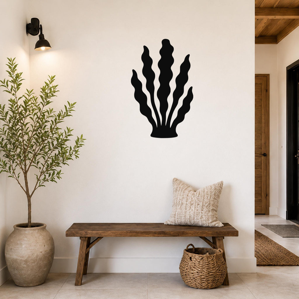 Black metal kelp wall art with wavy leaf cutouts, mounted on a white wall above a wooden bench in a living room.