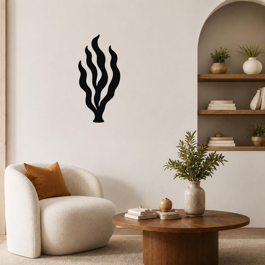 Black metal kelp seaweed wall art with flowing frond cutouts, mounted on a living room wall above a round wooden coffee table.