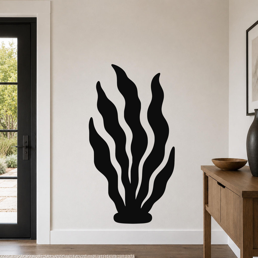 Black metal wall art in a kelp silhouette design with wavy leaf cutouts, mounted on a living room wall above a wooden console table.