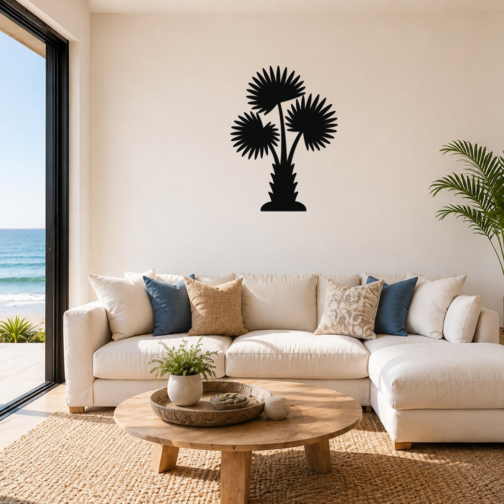 Black metal palm tree wall art with three fan-shaped fronds, mounted on a living room wall above a white sofa.