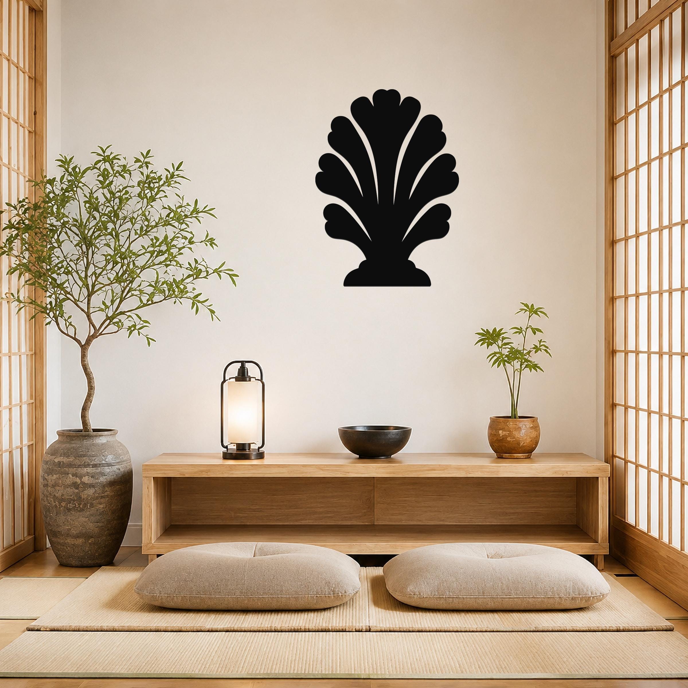 Black metal wall art in a coral or shell silhouette shape, mounted on a light-colored wall above a wooden console in a minimalist room with tatami mats and plants.