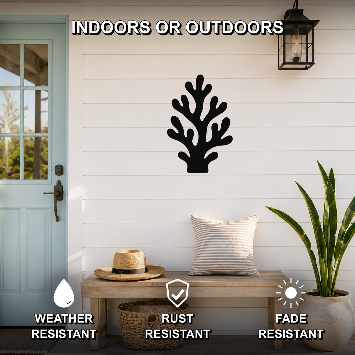 Black metal coral wall art with branching cutouts, mounted on a white shiplap wall above a wooden bench on a porch.