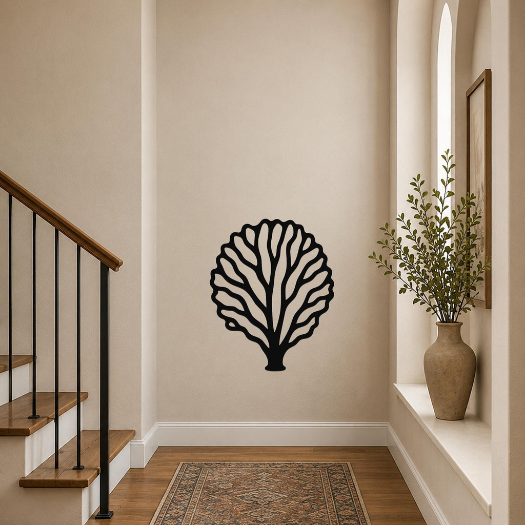 Black metal fan coral wall art with intricate branch cutouts, mounted on a hallway wall above a patterned rug near a staircase.
