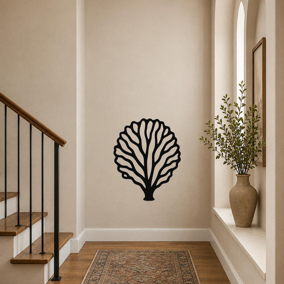 Black metal fan coral wall art with intricate branch cutouts, mounted on a hallway wall above a patterned rug near a staircase.