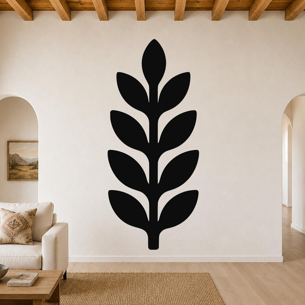 Black metal wall art in a leafy sprig silhouette, mounted on a living room wall above a sofa.