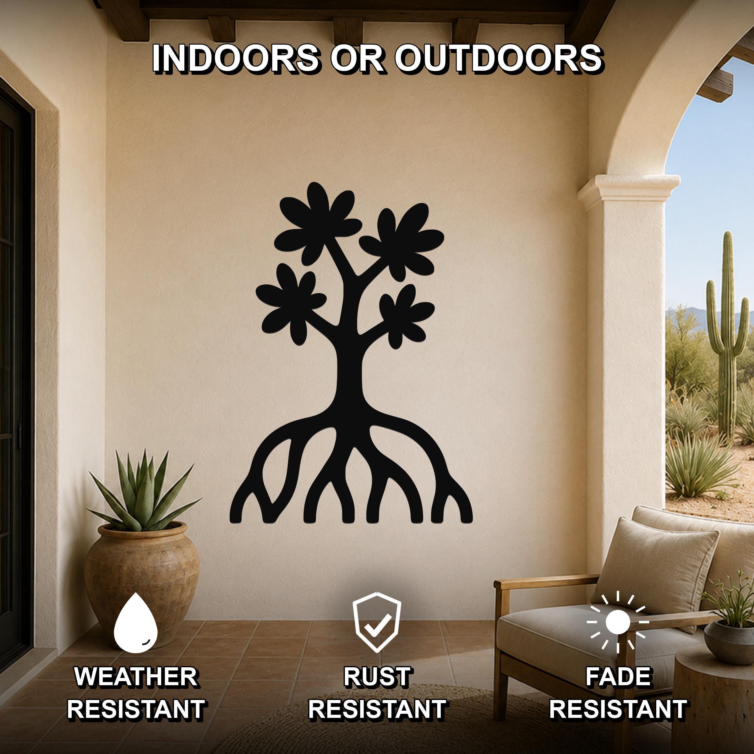 Black metal wall art featuring a tree silhouette with blooming flowers and visible roots, mounted on a beige outdoor patio wall above a chair and potted plant.