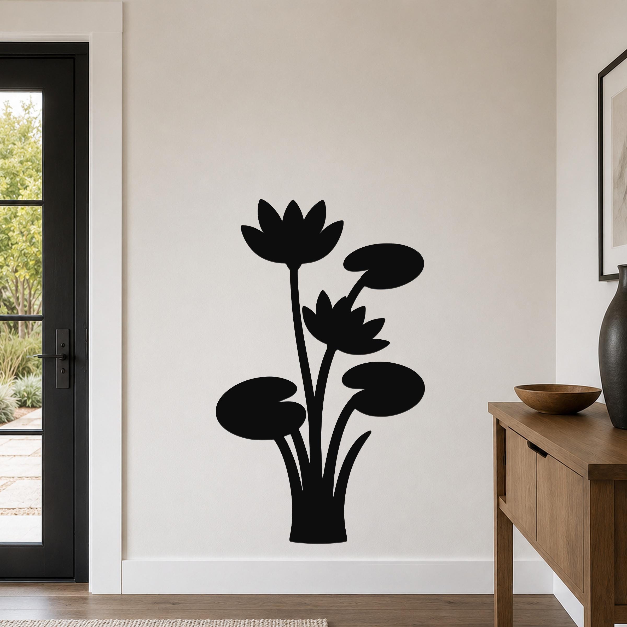 Black metal wall art silhouette of lotus flowers and lily pads, mounted on a living room wall above a wooden console table.