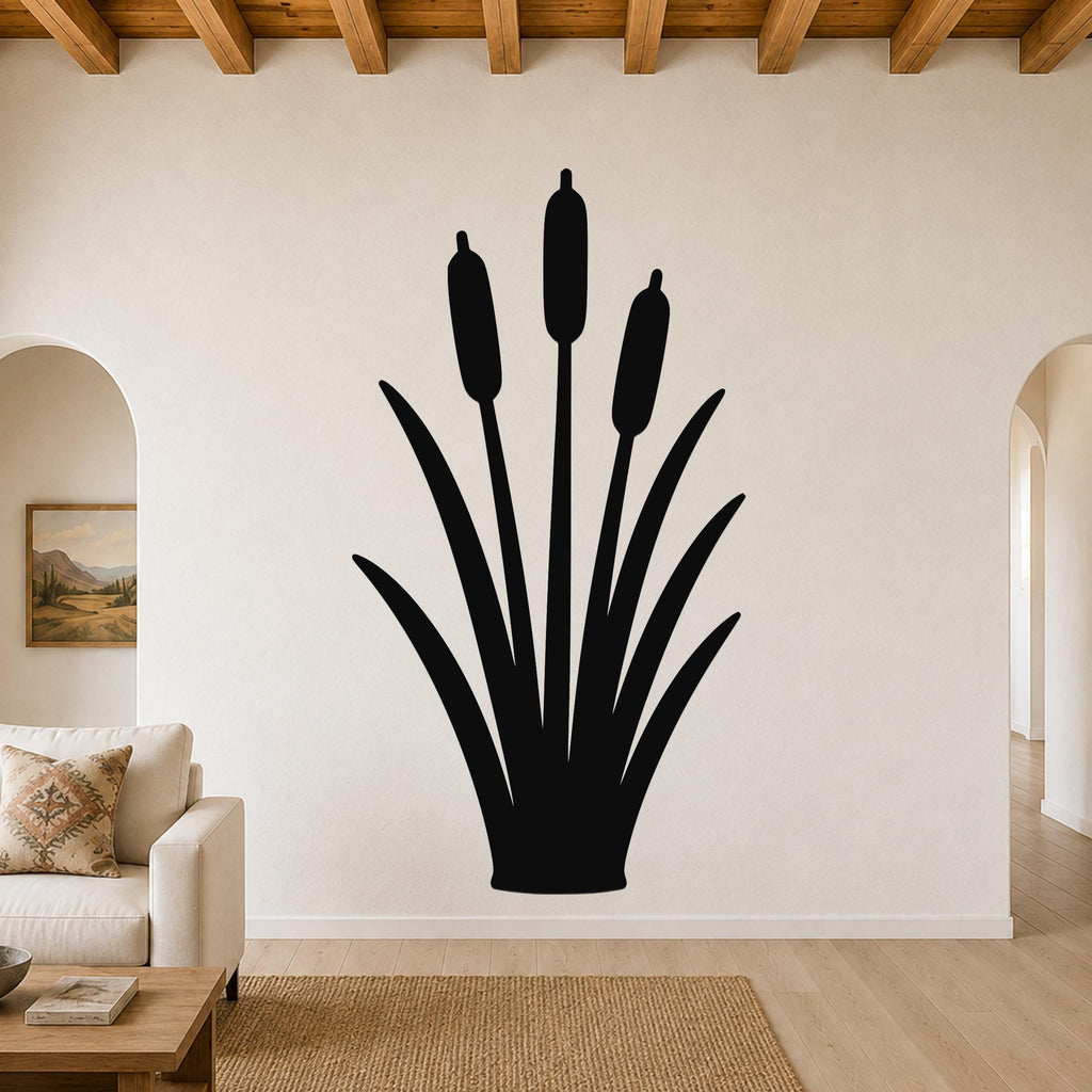 Black metal cattail wall art silhouette with three seed heads and long leaves, mounted on a living room wall above a sofa.