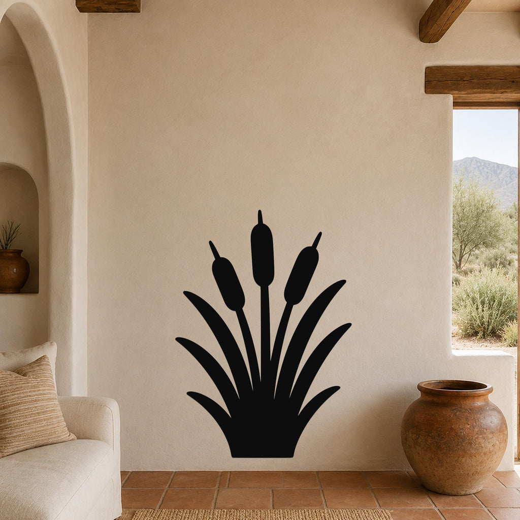 Black metal cattail wall art silhouette with three seed heads and long leaves, mounted on a beige living room wall above a sofa.