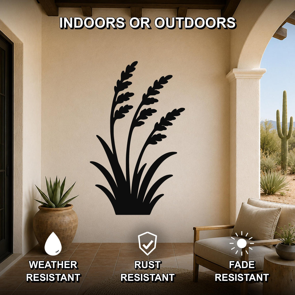 Black metal wall art of a wild grass silhouette, mounted on a beige outdoor patio wall above a potted succulent and a wooden chair.