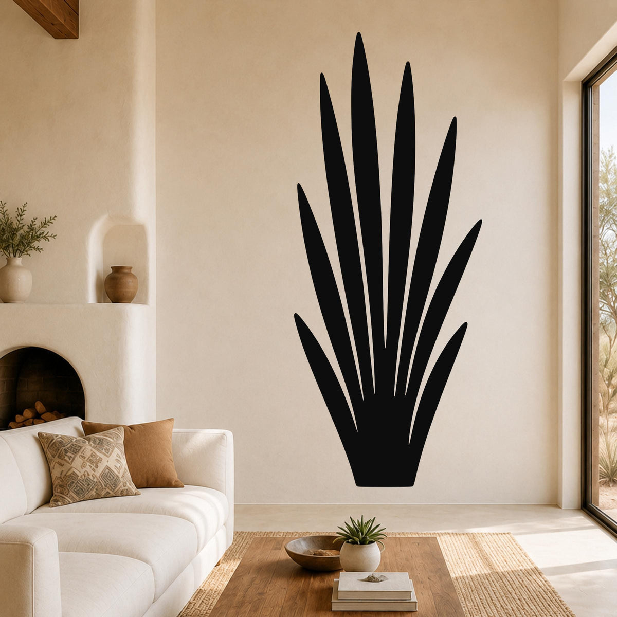 Black metal agave plant wall art with pointed leaf cutouts, mounted on a living room wall above a sofa.