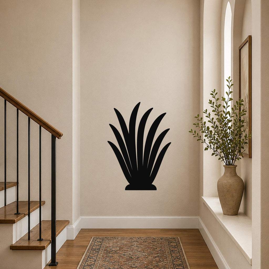 Black metal wall art in a stylized grass or agave silhouette, mounted on a hallway wall above a patterned rug near a staircase.