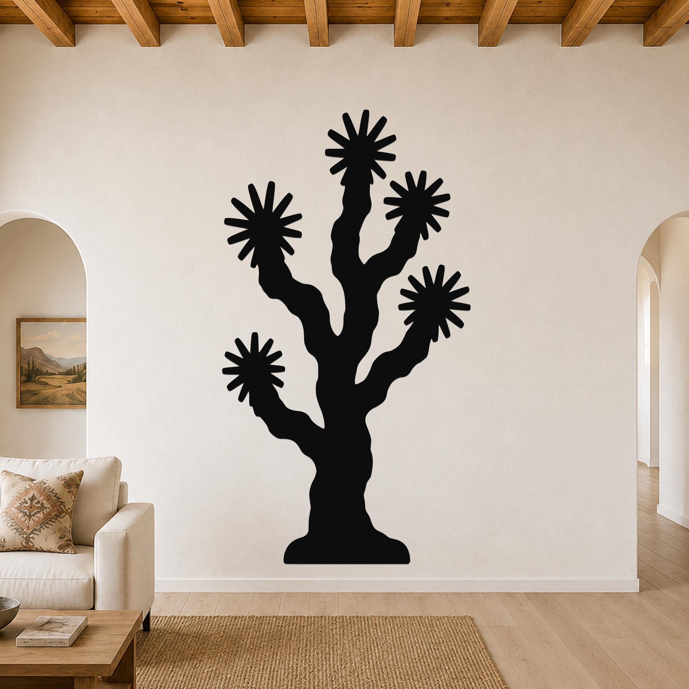 Black metal Joshua tree wall art with starburst cutouts, mounted on a living room wall above a sofa.