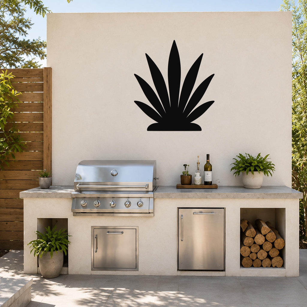 Black metal agave wall art silhouette mounted on a beige outdoor wall above a kitchen counter with a grill and storage.