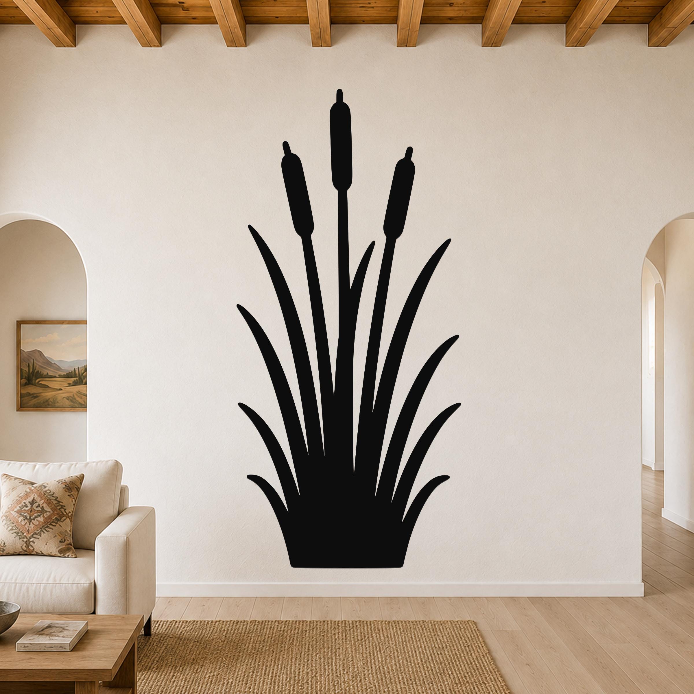 Black metal cattail wall art silhouette with three seed heads and long leaves, mounted on a living room wall above a sofa.