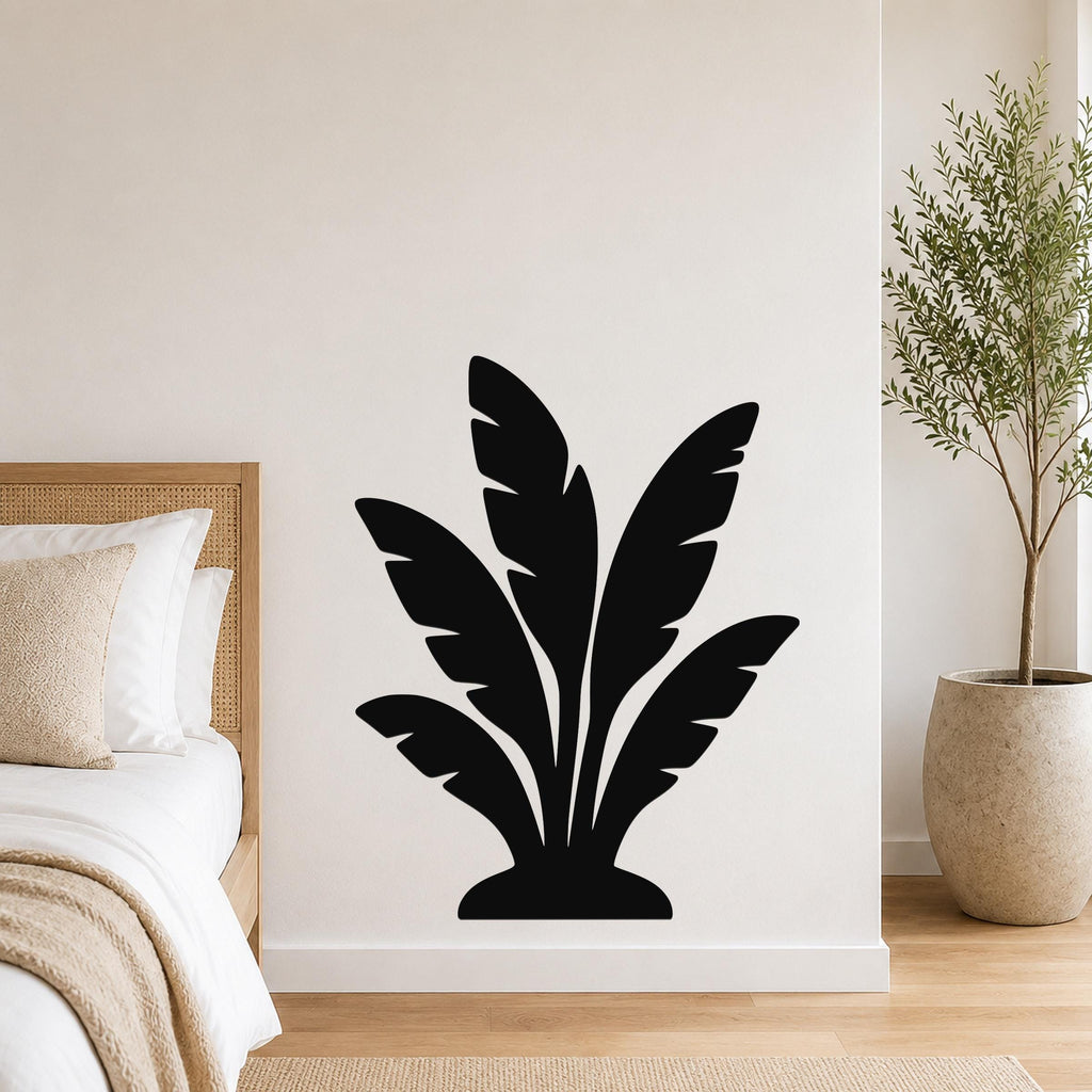 Black metal wall art in a tropical leaf silhouette design, mounted on a white bedroom wall above a bed.