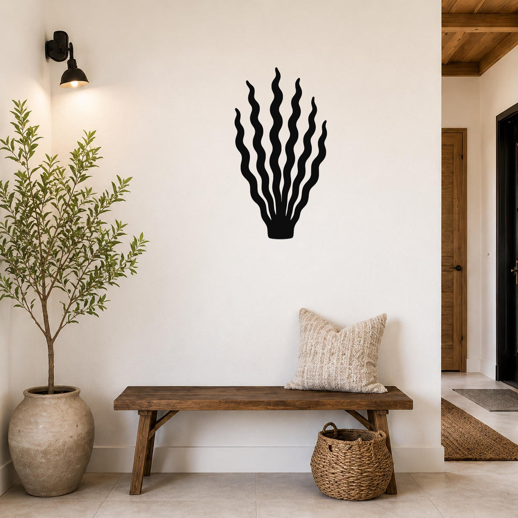 Black metal kelp wall art with wavy blade cutouts, mounted on a white wall above a wooden bench in a living room.