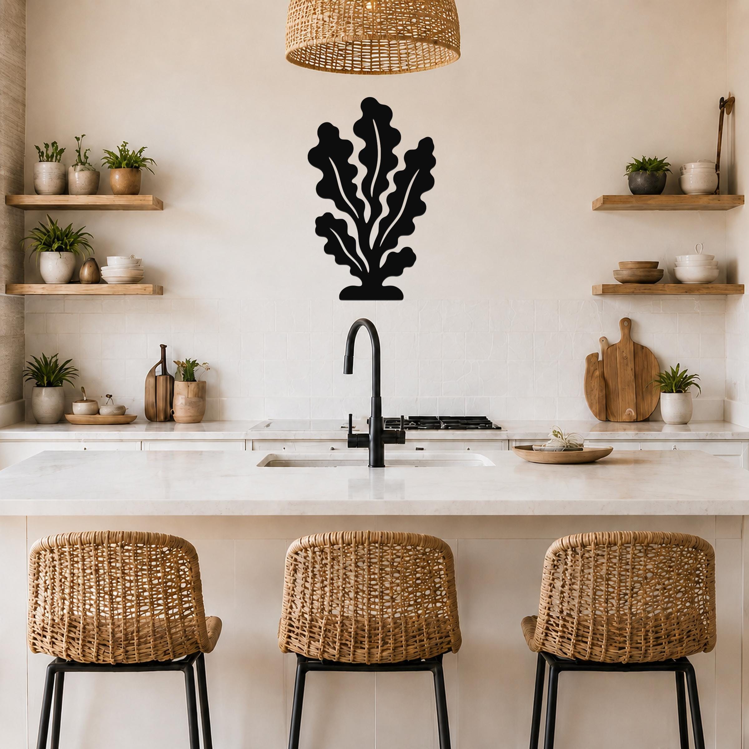 Black metal kelp wall art with leafy cutout design, mounted on a kitchen wall above a marble countertop.