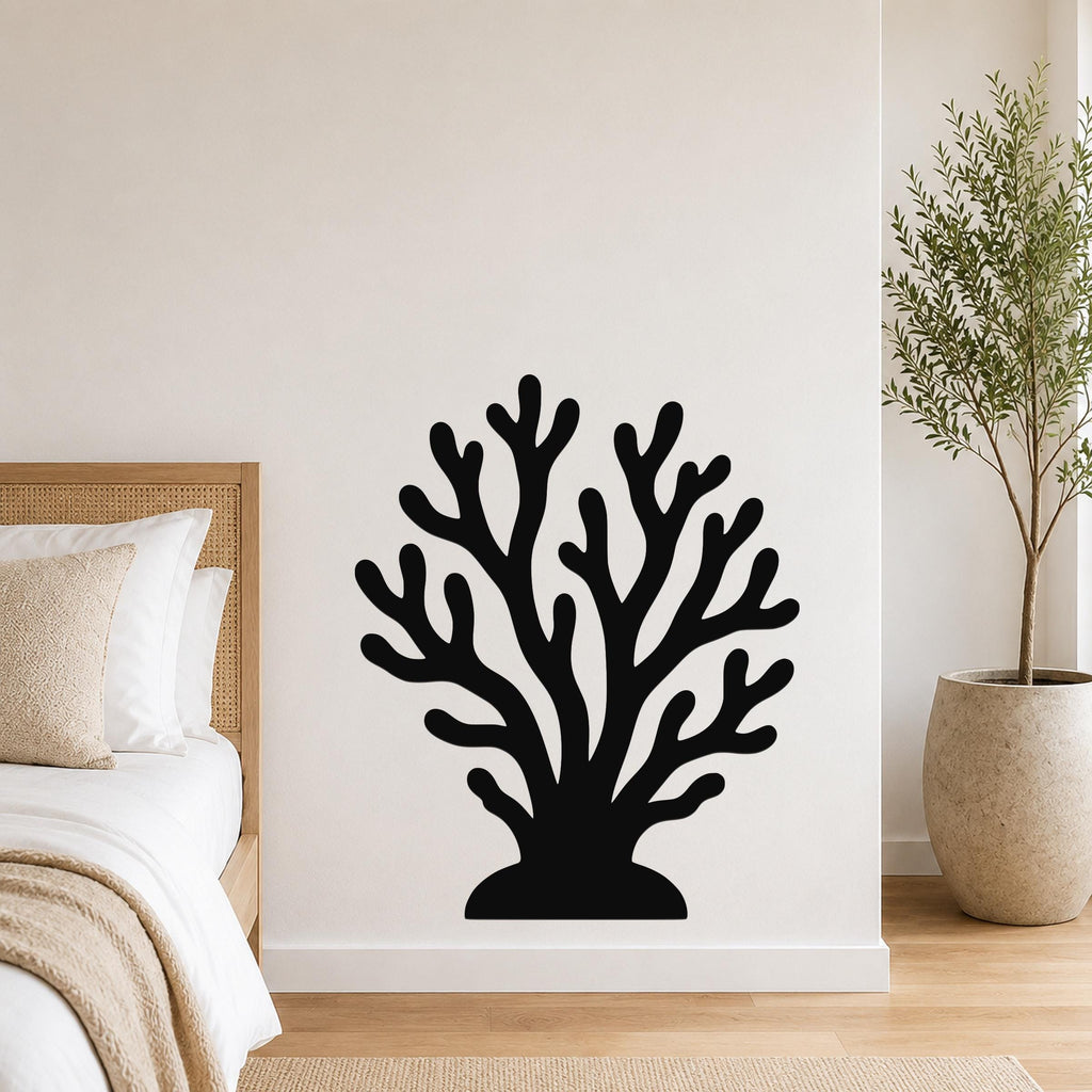 Black metal coral wall art with branching cutouts, mounted on a white bedroom wall above a bed.