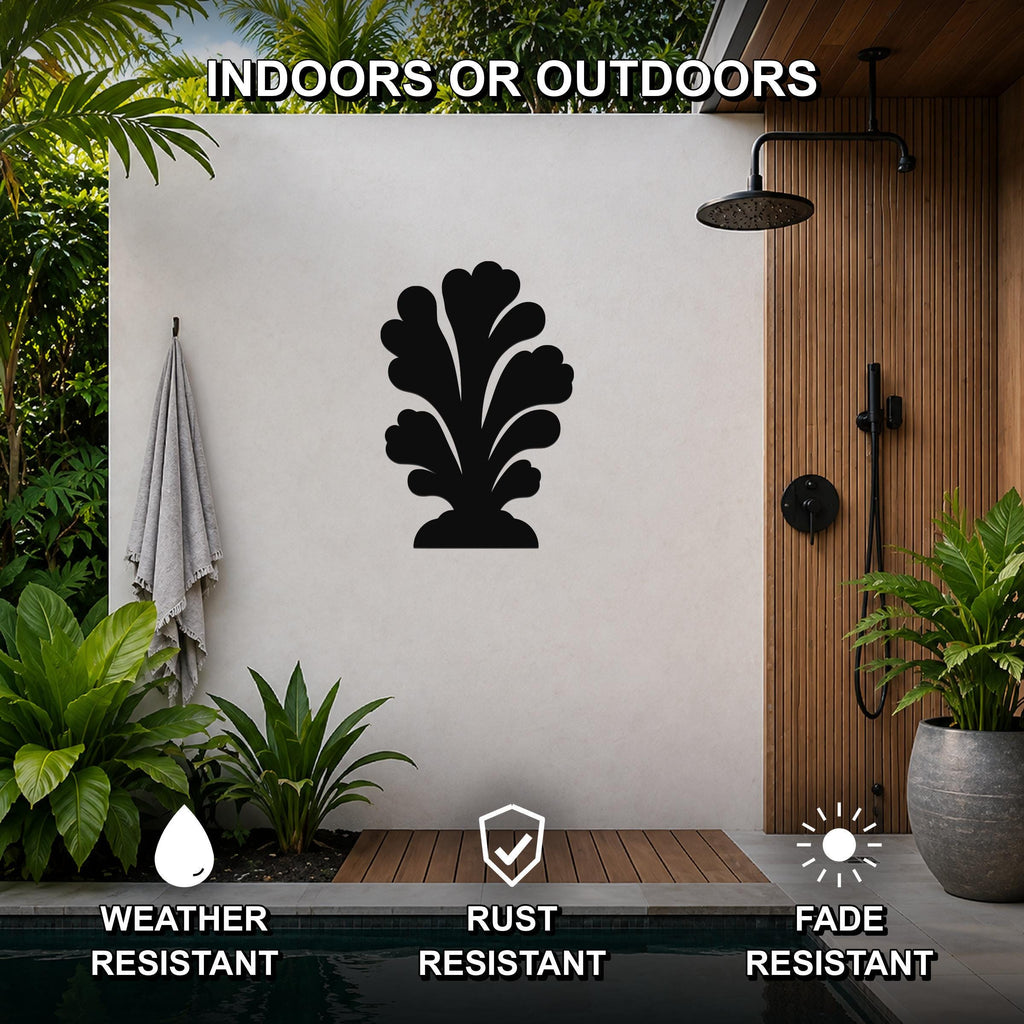 Black metal coral wall art with leafy cutout design, mounted on a white outdoor wall beside a wooden shower and pool area.