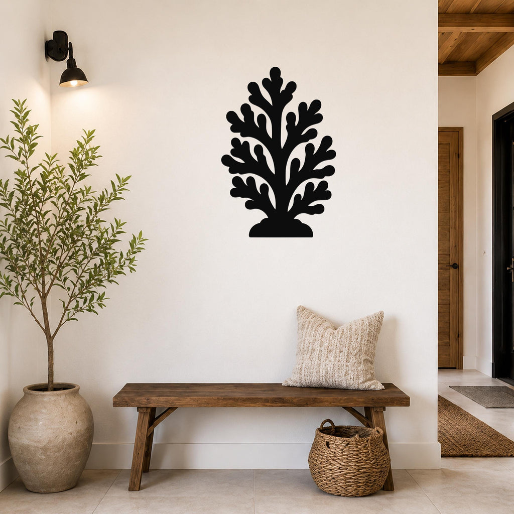 Black metal coral wall art with leafy branch cutouts, mounted on a white wall above a wooden bench in a living room.