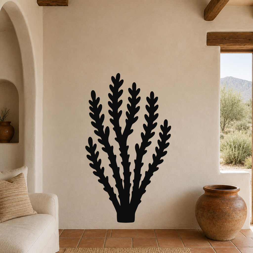 Black metal wall art in a desert branch silhouette, mounted on a beige living room wall above a sofa.
