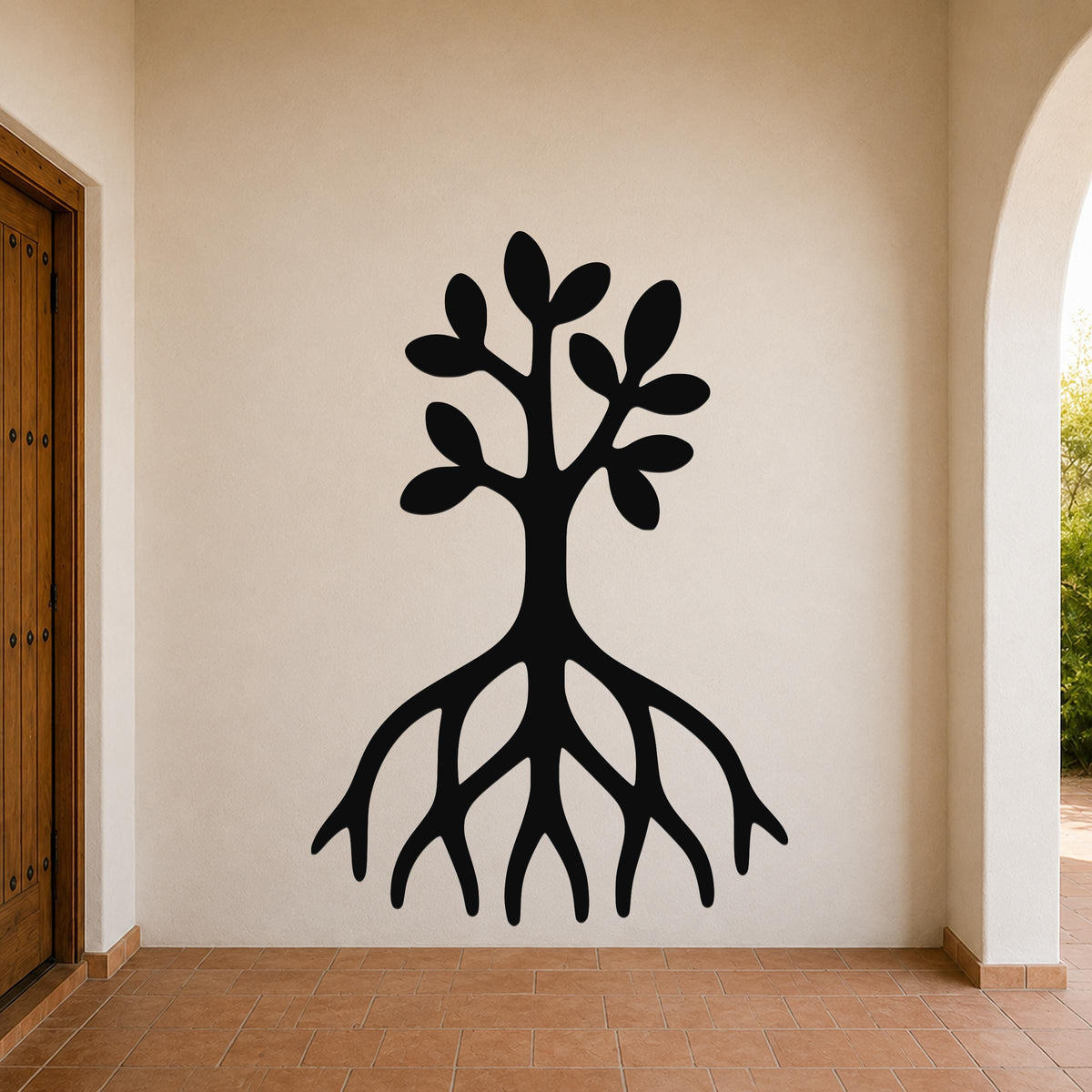 Black metal wall art cutout of a tree with visible roots and leafy branches, mounted on a beige wall in a covered entryway with terracotta flooring.