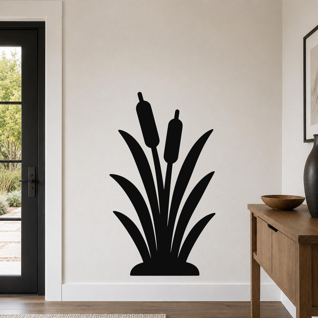 Black metal cattail wall art silhouette with two seed heads, mounted on a light-colored wall above a wooden console table in a modern entryway.