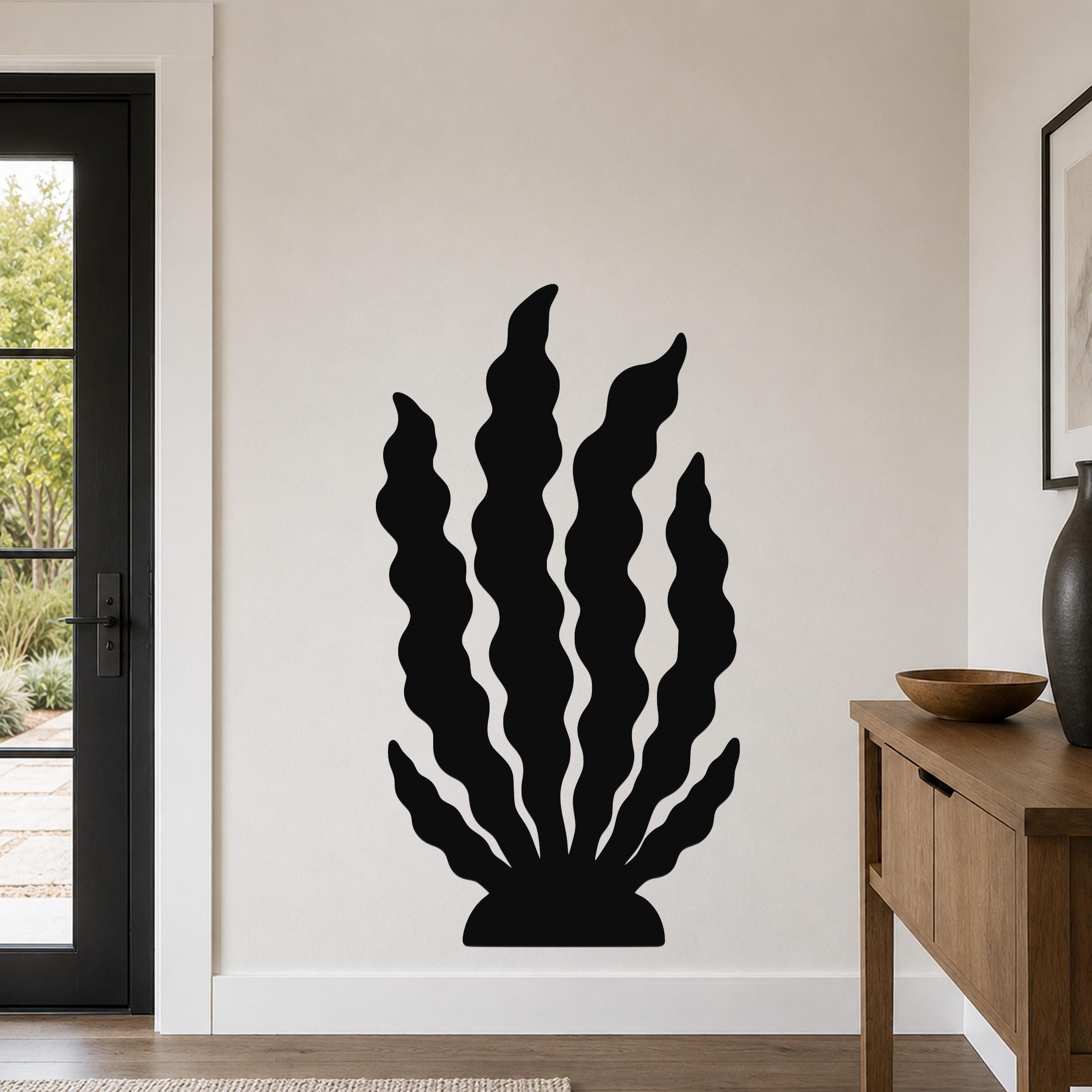 Black metal kelp wall art with wavy leaf cutouts, mounted on a light-colored wall in a modern entryway.