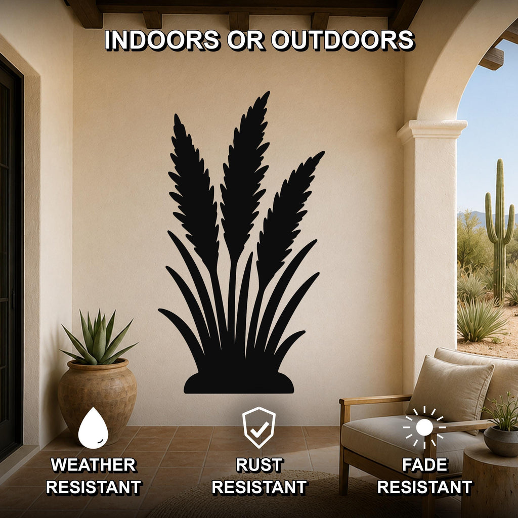 Black metal wall art silhouette of wild grass, mounted on a beige outdoor patio wall above a potted succulent and a wooden chair.