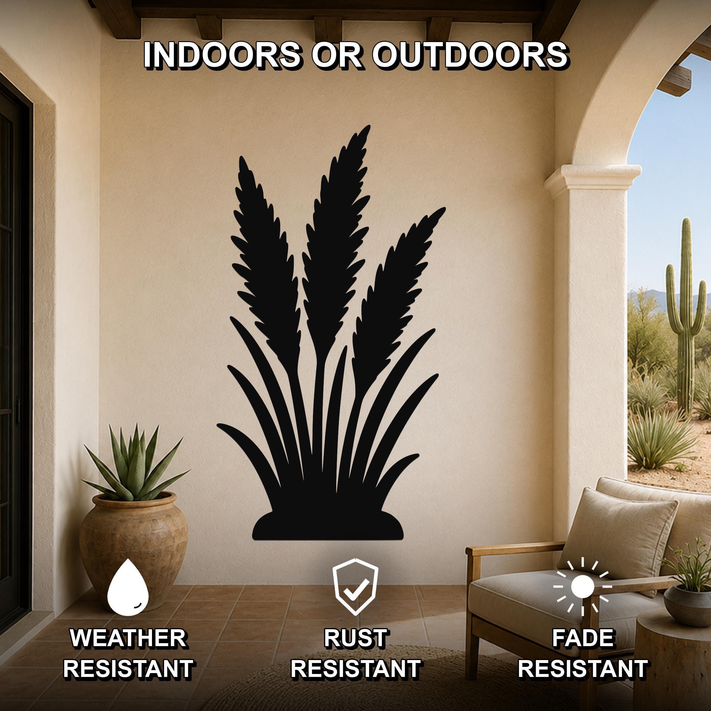 Black metal wall art silhouette of wild grass, mounted on a beige outdoor patio wall above a potted succulent and a wooden chair.