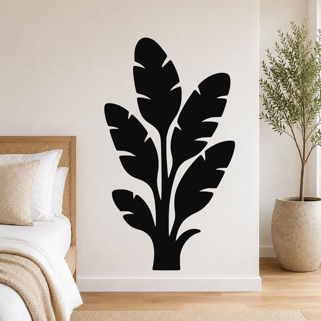 Black metal wall art in a tropical leaf silhouette design, mounted on a bedroom wall above a bed.