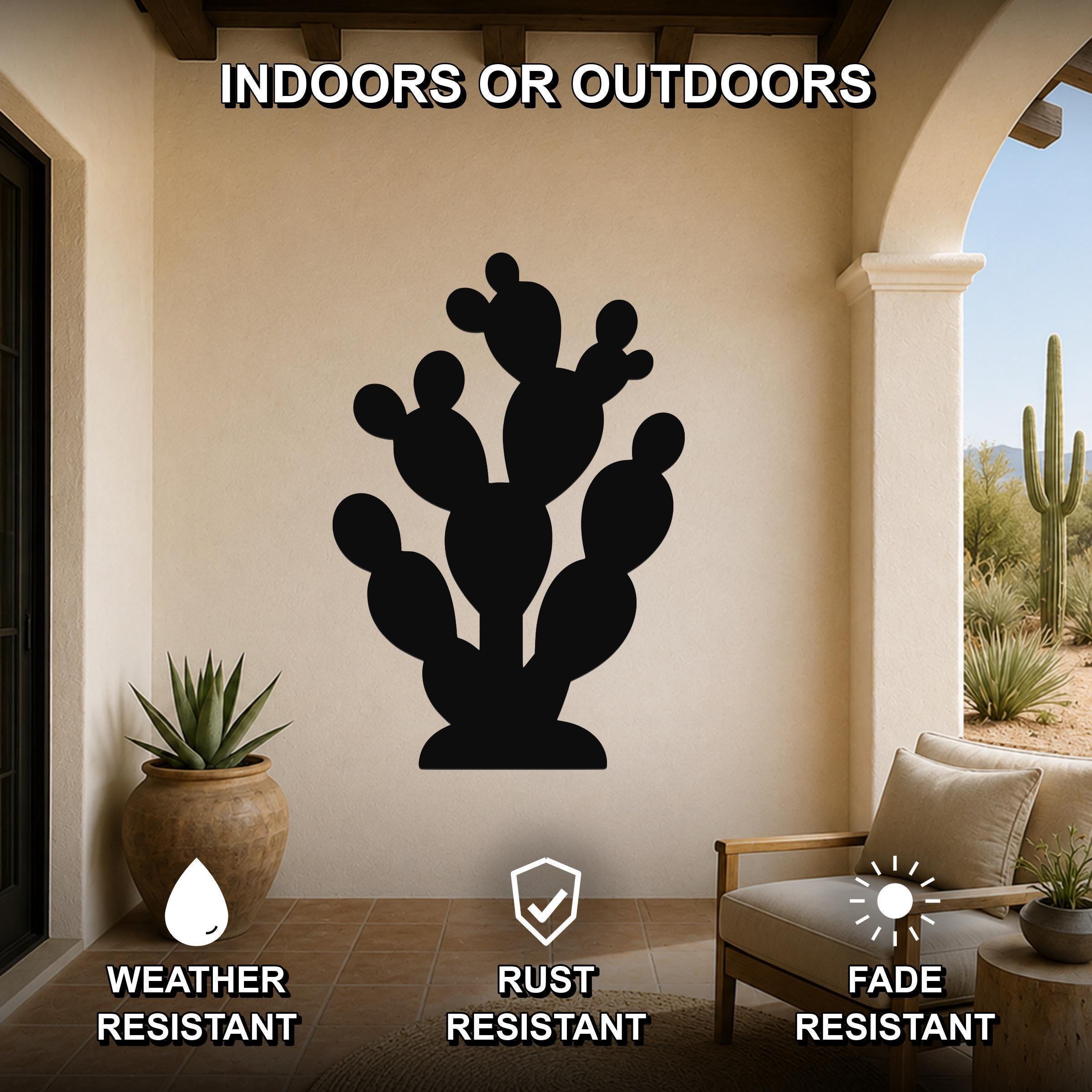 Black metal prickly pear cactus wall art with multiple segmented pads and cutout details, mounted on a beige wall in a covered patio with outdoor furniture and potted plants.